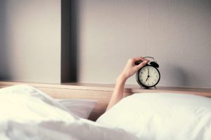 Person reaching up to turn off the alarm clock | Featured image for You snooze, you lose.