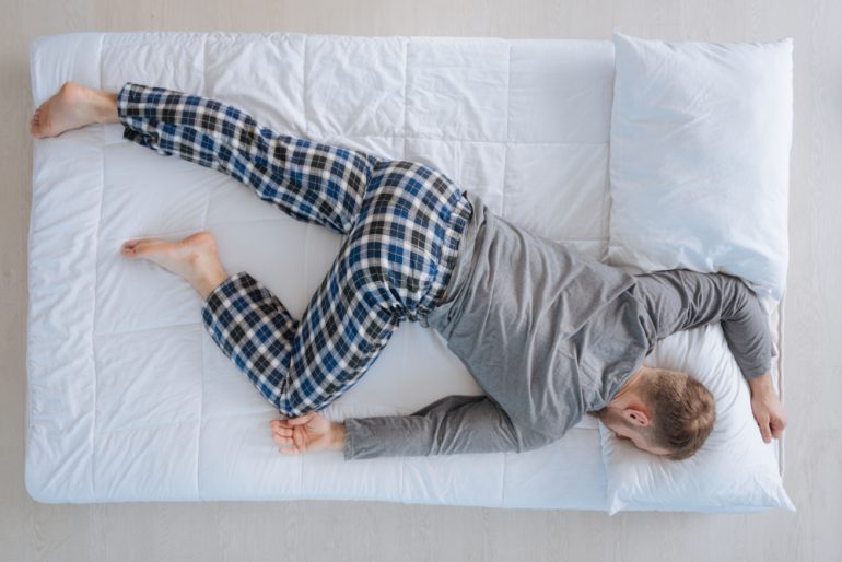 Adult man sleeping on his belly | Featured image for the What is the Right Position for Sleep blog from Wenatex.