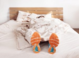 Man sleeping with sneakers on | Featured image for Can exercise help you sleep better at night?