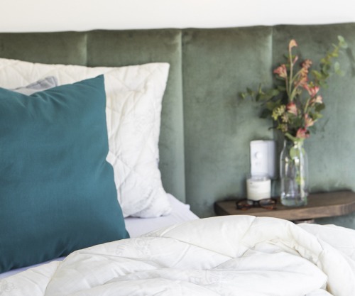 Green and white pillows on a bed | Featured image for Does a fresh bed help you sleep better?