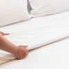 Person making a bed with Bella Donna Jersey fitted sheets | Featured image for Bella Donna Jersey Fitted Sheet (from $119.00).Bella Donna Jersey Fitted Sheet