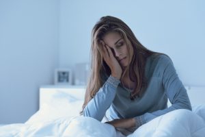 Depressed woman awake in the night | Featured Image for the Real Effects of Sleep Deprivation blog on Wenatex.