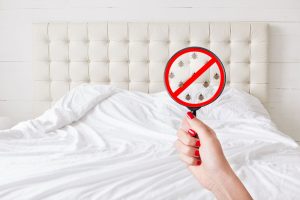 Magnifying glass showing cartoon image of bugs | Featured image for What really lies beneath your mattress.What really lies beneath your mattress