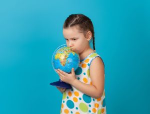 Young blonde haired girl kissing a globe | Featured image for Climate neutral into the future!