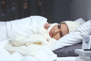 Woman in bed wrapped up in a winter quilt | Featured image for Sleeping well in winter.